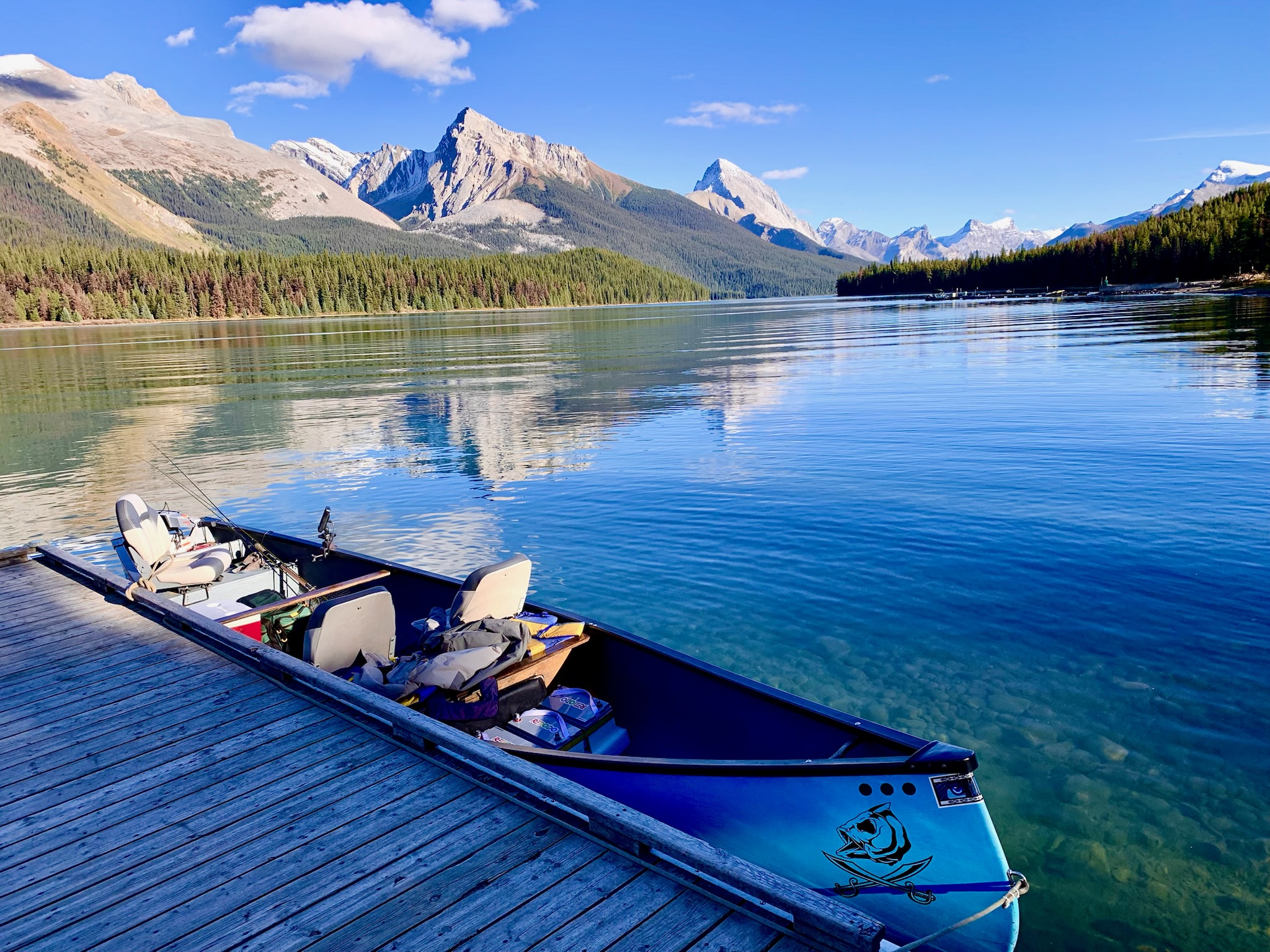 Blue canoe at dock on Maligne Lake with mountains